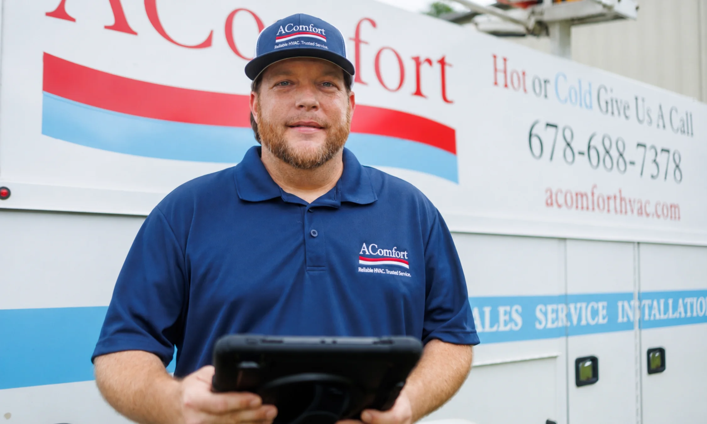 AComfort HVAC technician standing in front of company service vehicle in Griffin GA